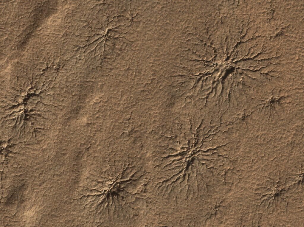 Sulcos no chão de Marte que se ramificam a partir de um centro, como patas de aranha.