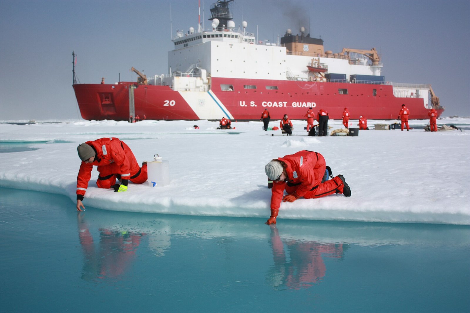 Dois pesquisadores coletam água de uma lagoa de derretimento sobre gelo no mar de Chukchi.
