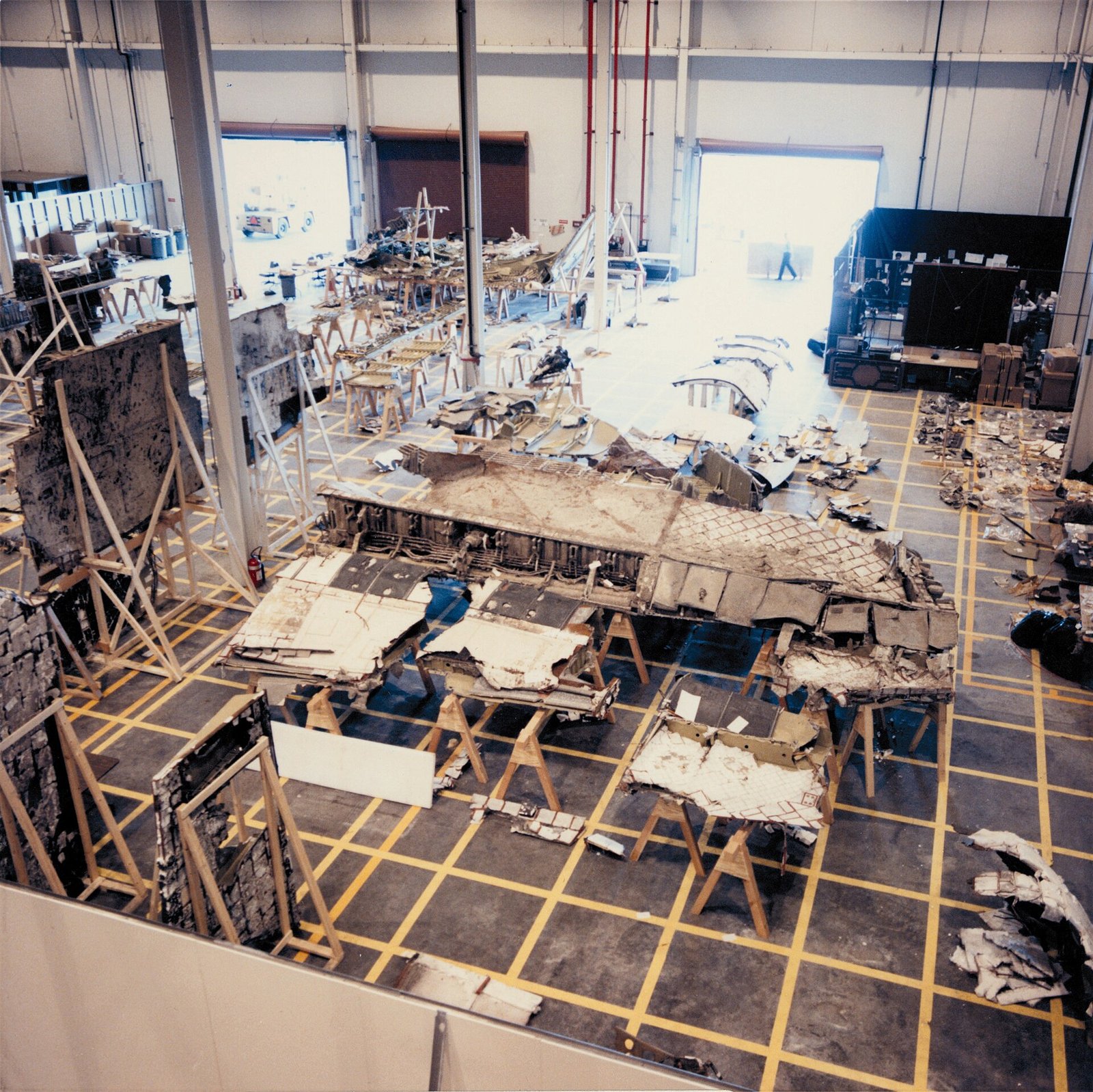 Destroços do ônibus espacial Challenger organizados no chão de um galpão para investigação.