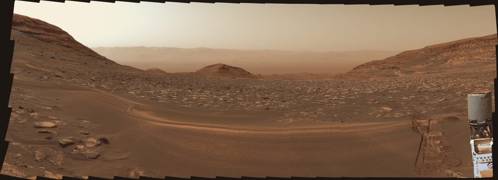 Panorama de Marte olhando encosta abaixo: uma crista de areia em primeiro plano e a planície da cratera ao longe, até a borda.