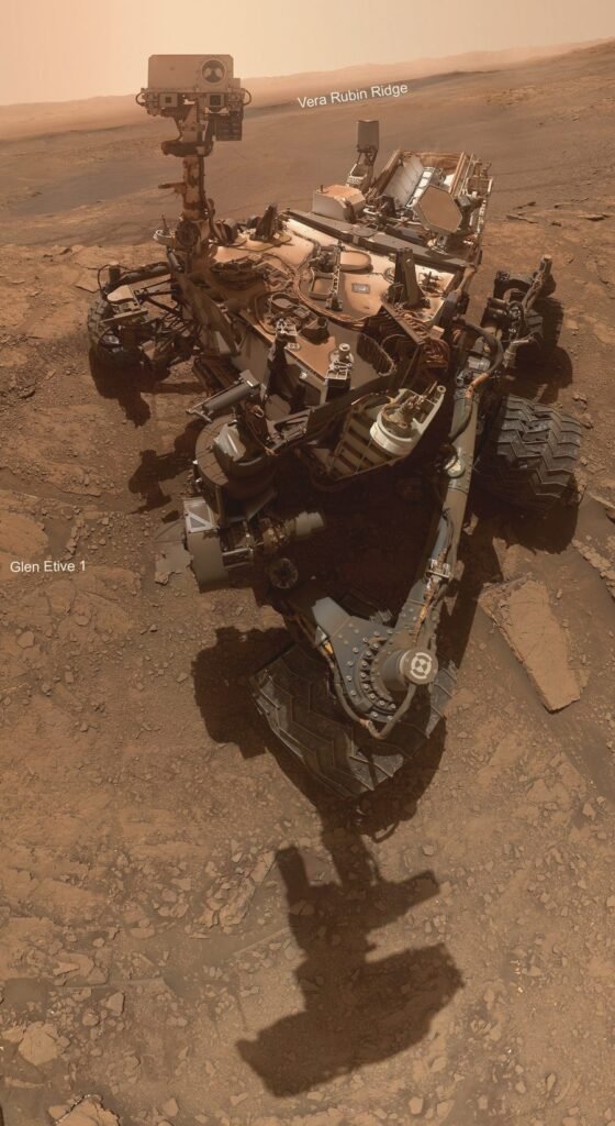 O robô Curiosity em Marte, com a paisagem da cratera Gale ao fundo.
