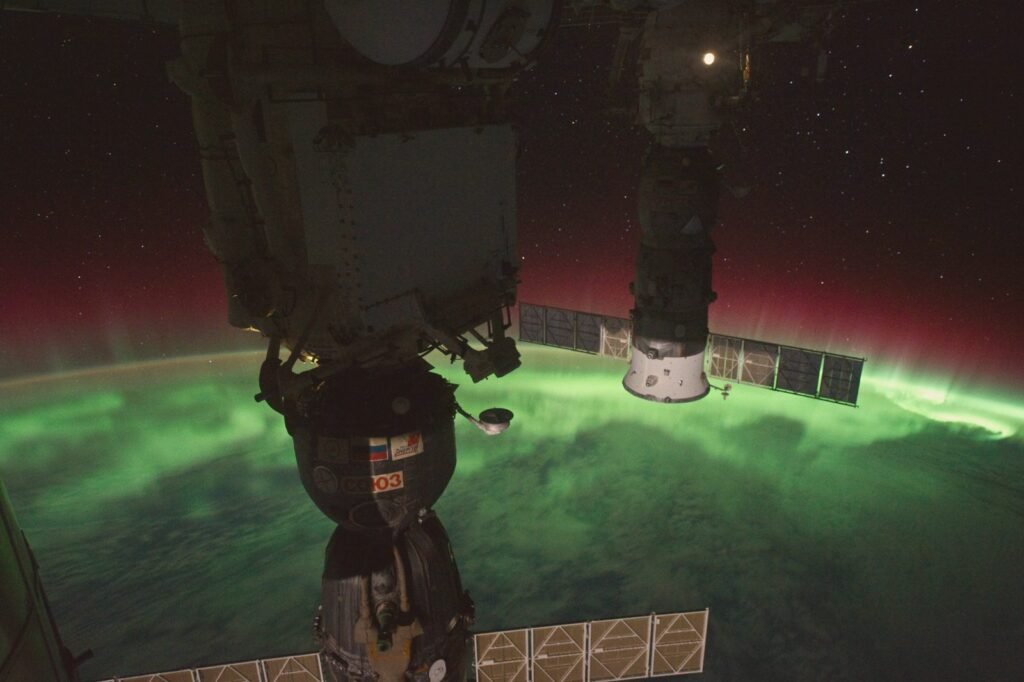 Faixa de luz verde sobre a curva da Terra, vista do espaço à noite.