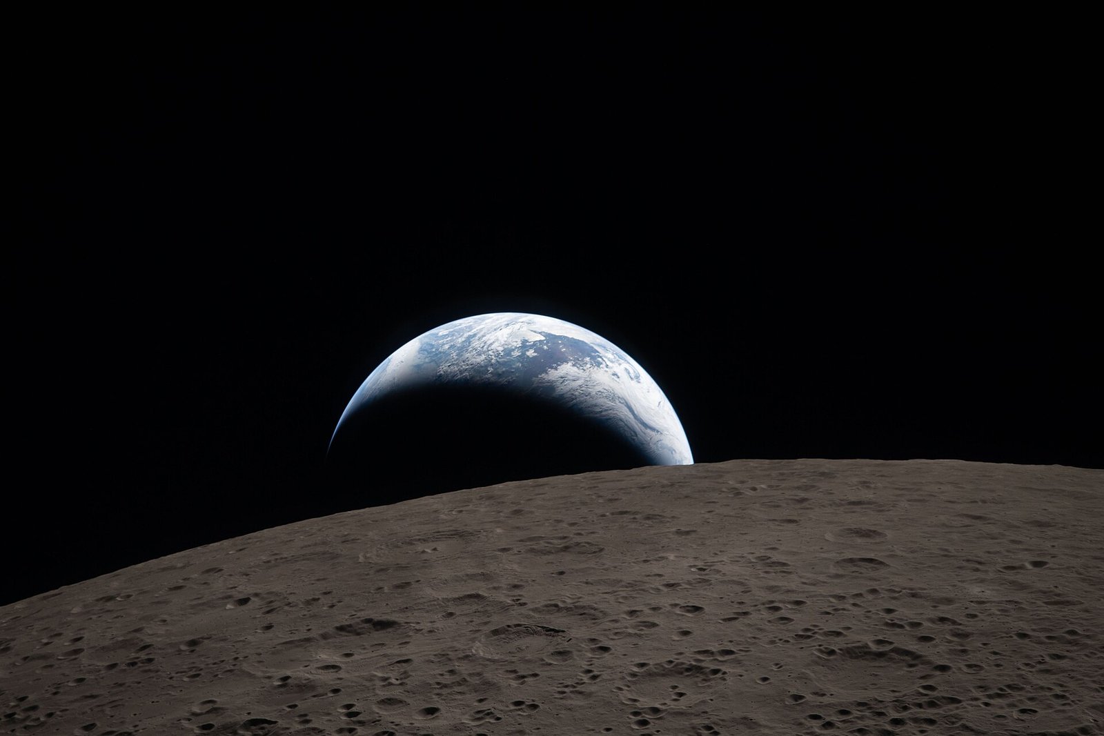 Terra azul parcialmente iluminada aparece junto à borda da Lua, cuja superfície cheia de crateras ocupa a frente da imagem.